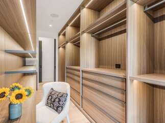 Step into this luxurious walk-in closet, featuring custom wood cabinetry with integrated LED lighting for a sophisticated ambiance.