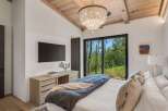 Experience luxury mountain living in this stunning bedroom featuring a king-sized bed adorned with plush pillows and a cozy duvet.