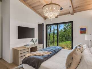 Experience luxury mountain living in this stunning bedroom featuring a king-sized bed adorned with plush pillows and a cozy duvet.