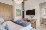 Experience modern luxury in this master bedroom featuring a king-sized bed with plush bedding and a striking abstract art piece.