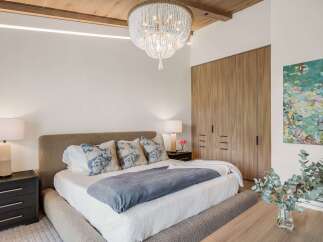 Experience luxurious comfort in this master bedroom, featuring a plush upholstered bed and elegant bedside tables.