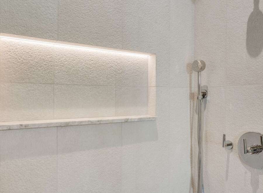 Experience modern luxury in this bathroom featuring a sleek, built-in shower niche with integrated lighting, perfect for displaying toiletries.
