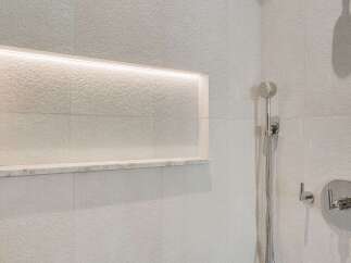 Experience modern luxury in this bathroom featuring a sleek, built-in shower niche with integrated lighting, perfect for displaying toiletries.