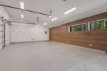 This spacious garage offers ample room for vehicles and storage, featuring a modern epoxy floor and a sleek wood-paneled accent wall.