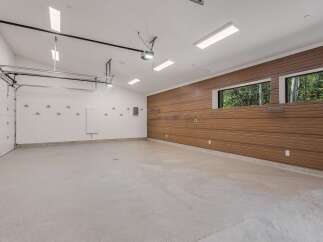 This spacious garage offers ample room for vehicles and storage, featuring a modern epoxy floor and a sleek wood-paneled accent wall.
