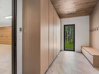Step into this modern entryway featuring sleek, floor-to-ceiling wood cabinetry for ample storage and a built-in bench for convenience.