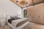 Experience luxury mountain living in this stunning bedroom featuring a vaulted wood-beamed ceiling and a striking modern chandelier.