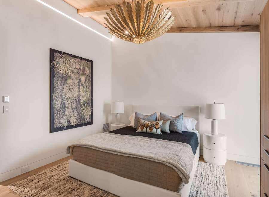 Experience luxury in this master bedroom, featuring a king-sized bed with a plush headboard and a striking botanical artwork.