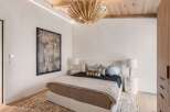 Experience luxury in this master bedroom, featuring a king-sized bed with a plush headboard and a striking botanical artwork.
