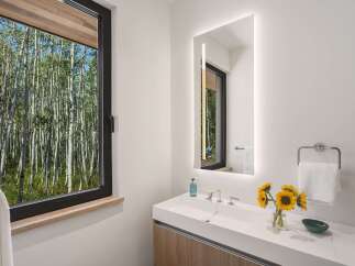 Experience modern luxury in this stunning bathroom, featuring a sleek double vanity with integrated sinks and a backlit mirror.