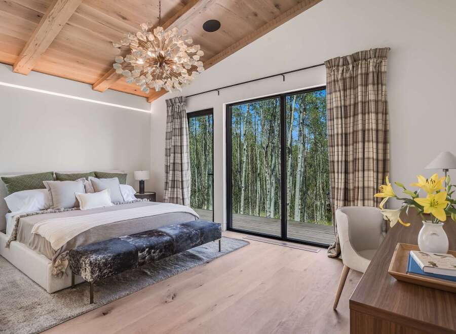 Experience luxurious mountain living in this stunning bedroom, featuring a grand king-sized bed adorned with plush pillows and a cozy throw.