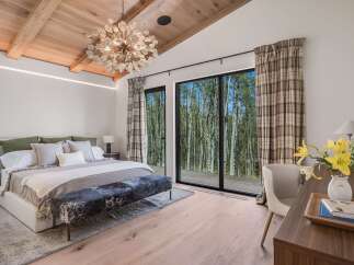 Experience luxurious mountain living in this stunning bedroom, featuring a grand king-sized bed adorned with plush pillows and a cozy throw.