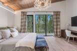 Experience luxurious mountain living in this stunning bedroom featuring a vaulted wood-beamed ceiling and a dramatic chandelier.