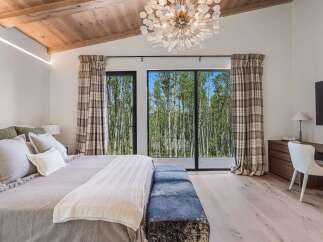 Experience luxurious mountain living in this stunning bedroom featuring a vaulted wood-beamed ceiling and a dramatic chandelier.