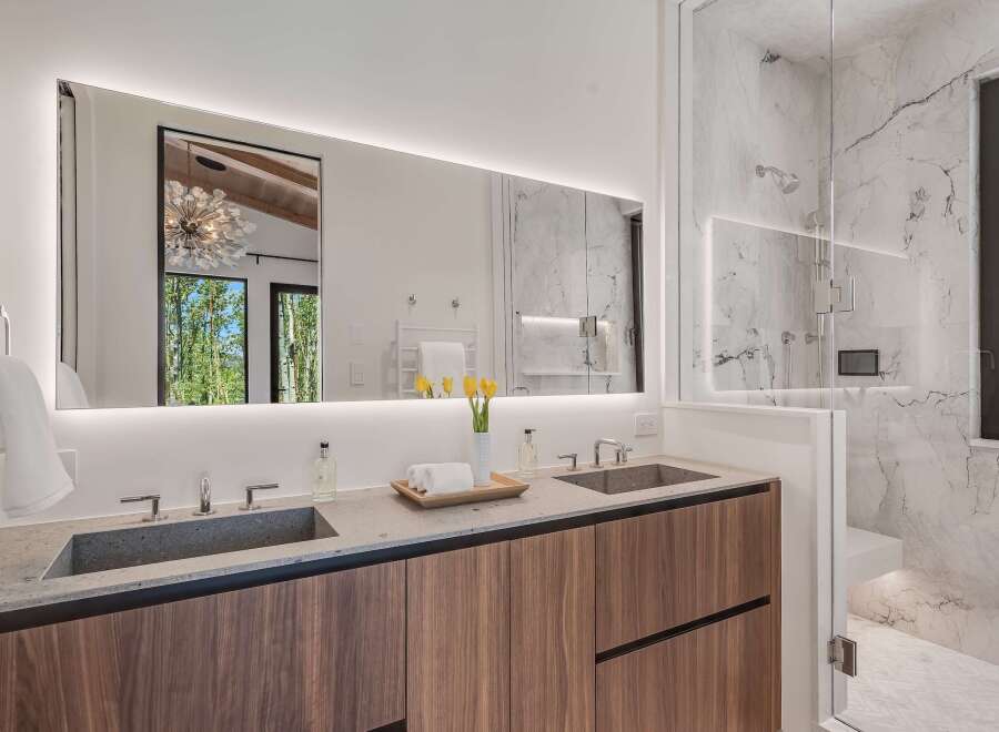 Experience luxury in this modern bathroom featuring a spacious double vanity with sleek stone countertops and integrated sinks.
