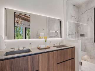 Experience luxury in this modern bathroom featuring a spacious double vanity with sleek stone countertops and integrated sinks.