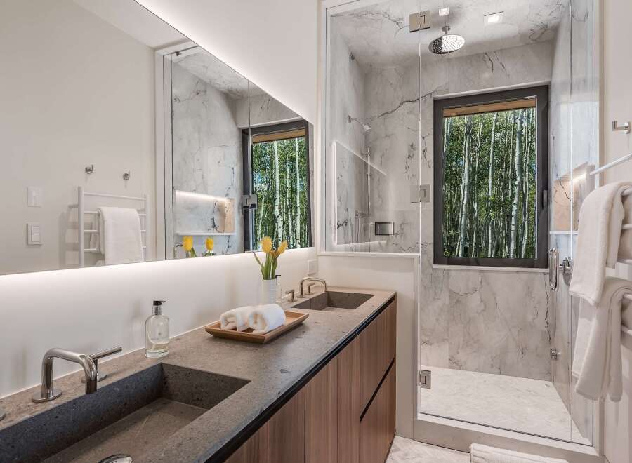 Experience luxury in this modern bathroom featuring dual sinks set in a sleek stone countertop.