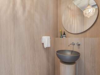 Experience modern luxury in this bathroom featuring a sleek, wall-mounted faucet and a stylish vessel sink.