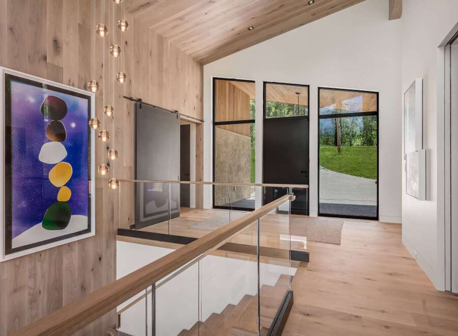 Experience modern luxury in this stunning entryway featuring a dramatic multi-tiered chandelier and a striking abstract art piece.