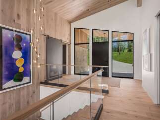 Experience modern luxury in this stunning entryway featuring a dramatic multi-tiered chandelier and a striking abstract art piece.