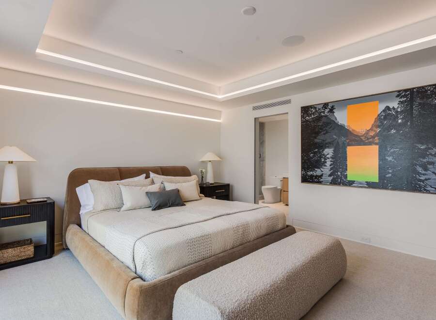 Experience modern luxury in this master bedroom, featuring a plush upholstered bed and a stylish boucle bench.