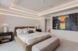 Experience modern luxury in this master bedroom, featuring a plush upholstered bed and a stylish boucle bench.