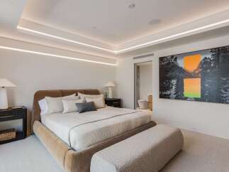 Experience modern luxury in this master bedroom, featuring a plush upholstered bed and a stylish boucle bench.