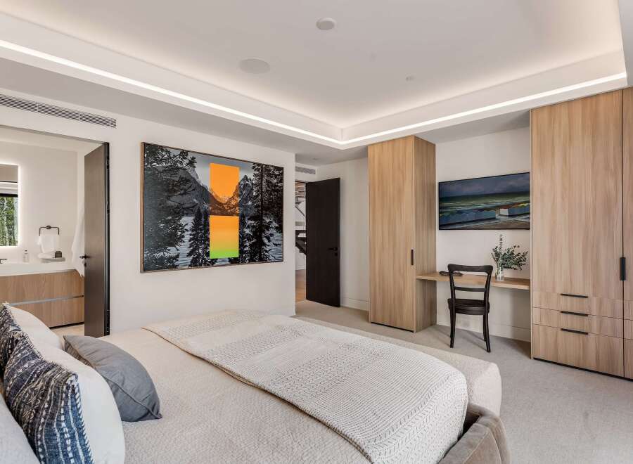 Experience modern luxury in this spacious bedroom, featuring a king-sized bed adorned with plush pillows and a textured throw.
