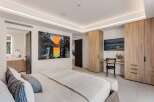 Experience modern luxury in this spacious bedroom, featuring a king-sized bed adorned with plush pillows and a textured throw.