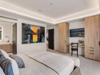 Experience modern luxury in this spacious bedroom, featuring a king-sized bed adorned with plush pillows and a textured throw.