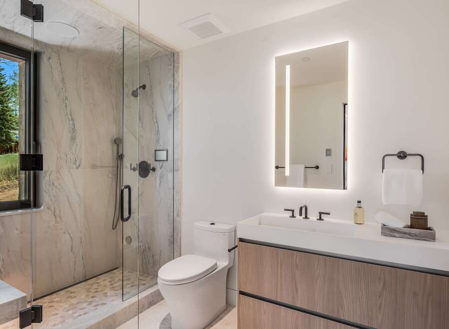 Experience modern luxury in this stunning bathroom, featuring a spacious walk-in shower with marble tile and a sleek vanity with a minimalist design.