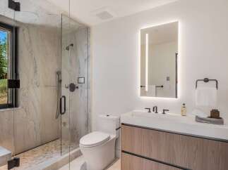 Experience modern luxury in this stunning bathroom, featuring a spacious walk-in shower with marble tile and a sleek vanity with a minimalist design.