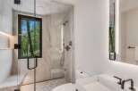 Experience luxury in this modern bathroom featuring a spacious walk-in shower with marble tile and a built-in bench.