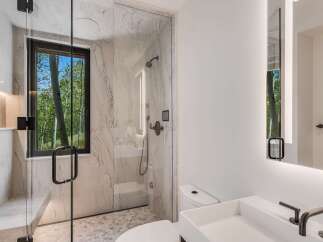 Experience luxury in this modern bathroom featuring a spacious walk-in shower with marble tile and a built-in bench.