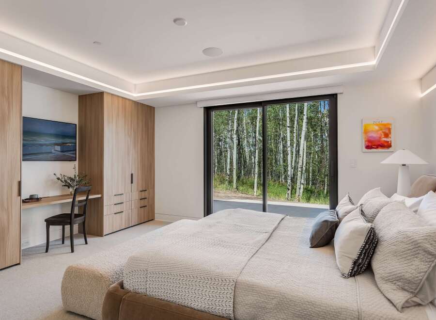 Experience luxury living with this stunning bedroom featuring a spacious king-sized bed adorned with plush pillows and a cozy throw.