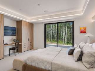 Experience luxury living with this stunning bedroom featuring a spacious king-sized bed adorned with plush pillows and a cozy throw.