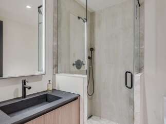 Experience modern luxury in this bathroom featuring a sleek vanity with a dark stone countertop and a minimalist black faucet.