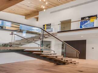Experience modern luxury in this stunning home featuring a floating staircase with glass railings and warm wood accents.