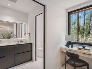 Experience modern luxury in this stunning bathroom featuring a sleek double vanity with integrated sinks and a large, illuminated mirror.
