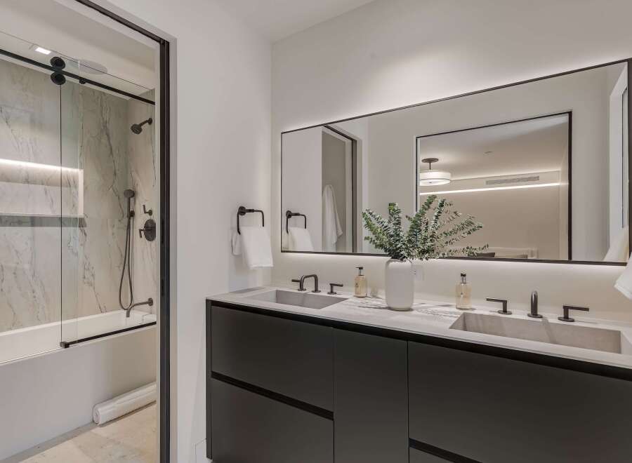 Experience modern luxury in this stunning bathroom featuring a sleek double vanity with concrete sinks and contemporary faucets.