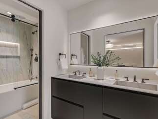 Experience modern luxury in this stunning bathroom featuring a sleek double vanity with concrete sinks and contemporary faucets.