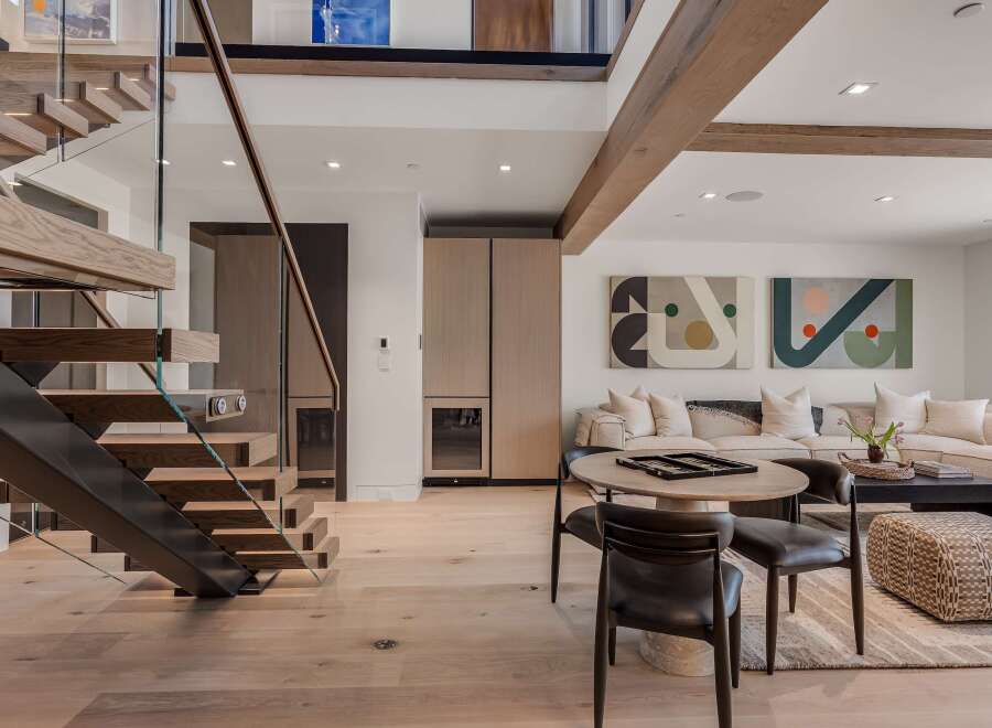 Experience modern luxury in this stunning living space featuring a floating wooden staircase with glass railings and integrated lighting.