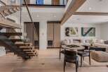 Experience modern luxury in this stunning living space featuring a floating wooden staircase with glass railings and integrated lighting.