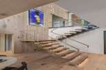 Experience modern luxury with this stunning staircase featuring floating wooden treads and sleek glass railings.