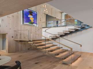 Experience modern luxury with this stunning staircase featuring floating wooden treads and sleek glass railings.