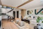 Experience modern living in this stunning open-concept space, featuring a sleek floating staircase with glass railings and exposed wooden beams.