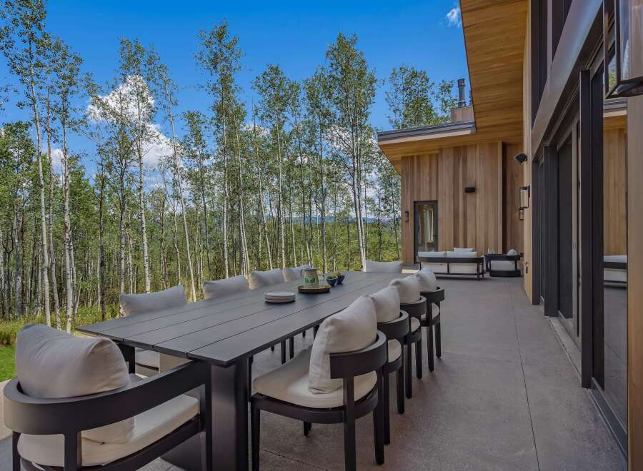 Enjoy al fresco dining with this stunning outdoor patio featuring a large dining table and comfortable seating, perfect for entertaining guests.