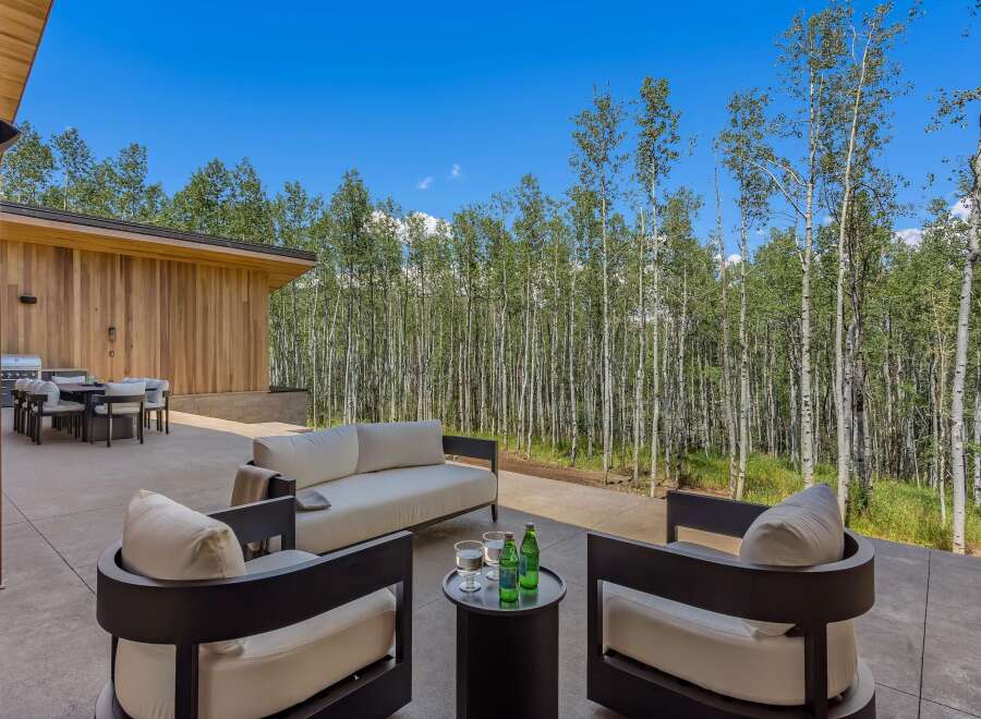 Enjoy outdoor living at its finest on this expansive patio, featuring a modern outdoor dining set and a comfortable seating area perfect for relaxation.