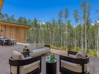 Enjoy outdoor living at its finest on this expansive patio, featuring a modern outdoor dining set and a comfortable seating area perfect for relaxation.