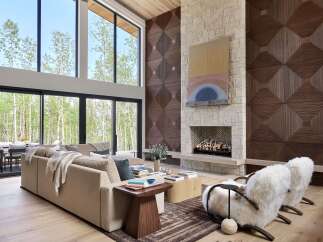 Experience luxury living in this stunning modern great room, featuring soaring ceilings and expansive windows that offer breathtaking views of the surrounding forest.